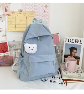 Dettaglio dello zaino in nylon azzurro con un simpatico ciondolo a forma di orso bianco