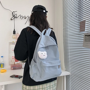 Dettaglio dello zaino celeste impermeabile con ciondolo a forma di orso bianco e tasche