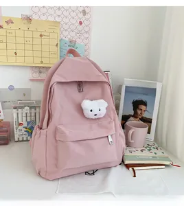 Dettaglio zaino in nylon rosa con tasche con cerniera e ciondolo a forma di orso