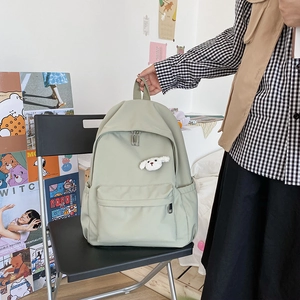 Dettaglio dello zaino in nylon verde chiaro impermeabile con un ciondolo a forma di cane