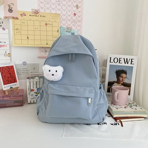 Dettaglio dello zaino in nylon impermeabile azzurro con ciondolo a orso e tasche