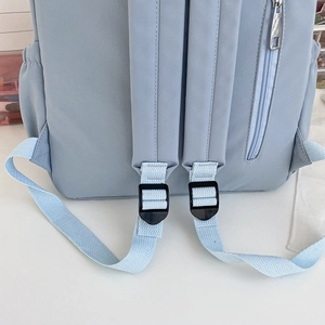 Vista dettagliata dello zaino celeste con spallacci regolabili e tasca con zip sul retro