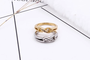 Detail of interlocking infinity figure-eight rings with crystal accents in gold and silver
