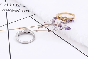 Detail of gold and silver infinity rings with tiny white zircons on a textured background