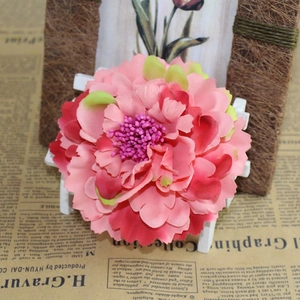 Macro detail of a pink gradient artificial peony flower hair clip on a white wooden stand