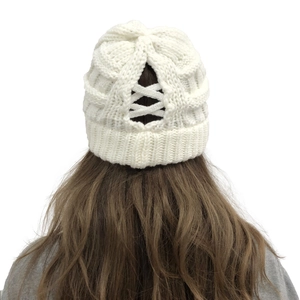 Detail of white chunky knit beanie with ponytail opening and cross strap design