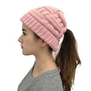 Detail of pink knitted messy bun beanie showing elastic ponytail opening and cable texture