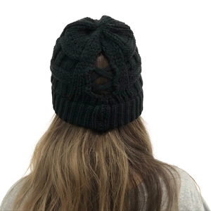 Macro view of black cable knit ponytail beanie featuring elastic criss-cross back opening