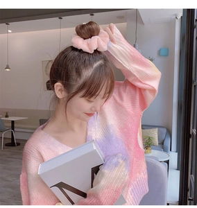 Close-up of a pink plush scrunchie worn on a ponytail to show texture and soft material