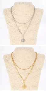 Detail of layered gold and silver necklaces with round coin pendants on a beige bust