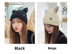 Detail of winter knitted hat with cute cat ears and CAT logo tag in black and beige