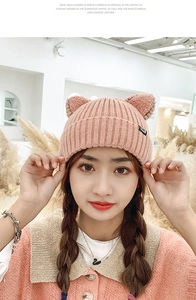 Close-up of pink knit beanie with cute cat ears and woven letter label for winter