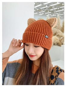 Detailed close-up of orange knitted cat ear beanie with ribbed texture and CAT label