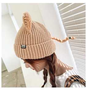 Detailed close-up of beige knit beanie with cute cat ears and a small CAT woven label