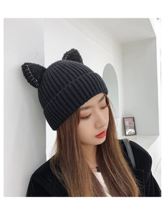 Detail view of a black knitted winter hat featuring cute cat ears with white stitching
