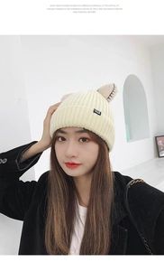 Close-up of cream knit beanie featuring cute cat ears and small CAT textile label detail