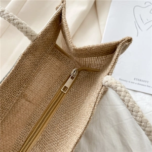 Detail view of natural jute tote bag featuring a sturdy metal zipper and woven rope handle