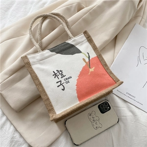 Detail of canvas bento bag with orange print and text on soft beige fabric background