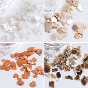 Detailed close-up of colorful iridescent shell flakes for nail art in four metallic shades