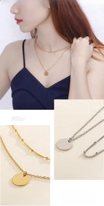 Macro detail of layered gold and silver dainty necklaces with polished round disc pendants