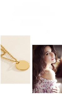 Close-up of golden round disc pendant and thin chain showing smooth polished metal finish
