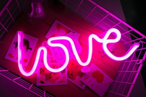 Pink LED LOVE neon sign glowing inside a white metal basket for party decoration