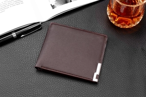 Brown leather men's wallet with silver metal trim on a professional business desk setup