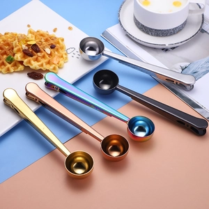 Five colored stainless steel coffee scoops with integrated sealing clips on a pastel background