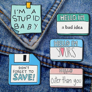 Set of five creative square colorful enamel pins with slogans pinned on denim fabric