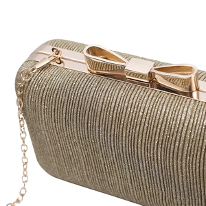 Elegant gold pleated evening clutch bag with a shiny metal bow clasp and chain strap