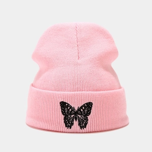 Close-up of pink knitted beanie featuring detailed black butterfly embroidery and folded cuff