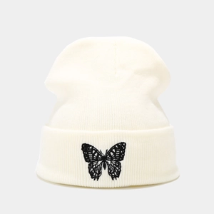 Detail of cream knit beanie featuring black butterfly embroidery and ribbed cuff