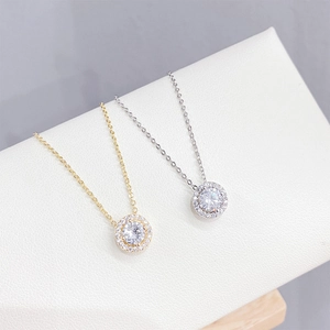 Elegantes collares con colgante halo en oro y plata con circonitas en un soporte blanco