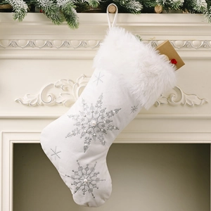 White velvet Christmas stocking with silver snowflakes and pearls on a white fireplace