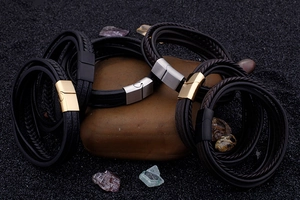 Close-up of multilayer braided leather bracelets with gold, silver, and black magnetic clasps