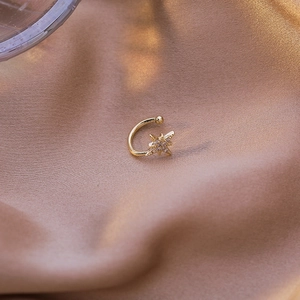Close-up of golden starburst ear cuff with micro-pave zircons on champagne silk