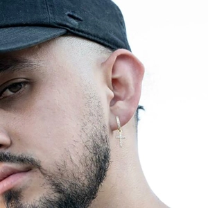 Close-up of a men's gold cross earring with pavé zircon stones on a male model's ear