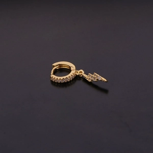 Détail d'une créole dorée avec pendentif éclair en zircons sur fond noir élégant