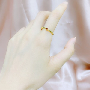 Minimalist gold-plated zircon ring with red round stone on pink silk background