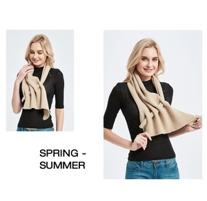 Detail of light beige knitted scarf showing intricate mesh cut-out texture and soft fabric