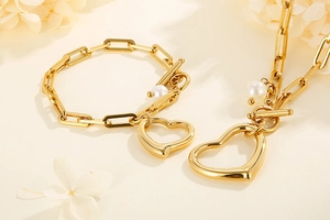 Detail of gold paperclip chain necklace and bracelet set with heart and pearl charms