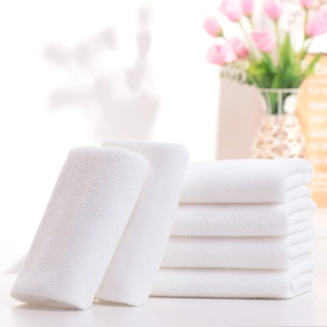 Plush white cotton towels for hotel use neatly stacked showing soft and absorbent texture