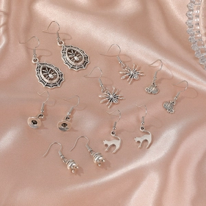 Detailed view of 6 pairs of vintage silver Halloween earrings on pink silk background