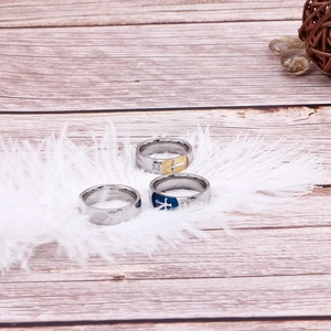 Dettaglio di tre anelli a croce nei colori argento, oro e blu posati su piume soffici