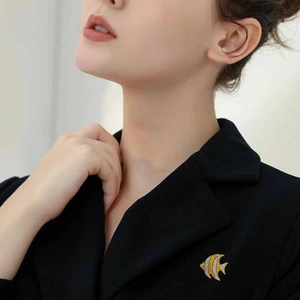 Elegant fish brooch with yellow and white crystals on a black suit lapel