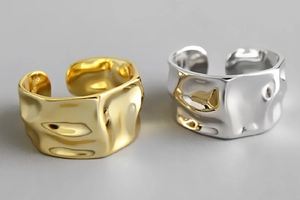 Detail view of irregular hammered texture on gold and silver wide geometric open rings