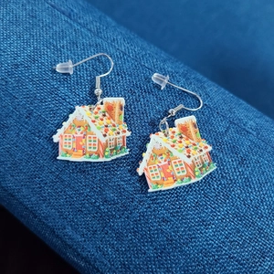 Detailed close-up of festive gingerbread house earrings on dark blue textured fabric