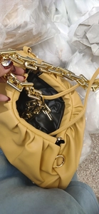 Detailed top view of a yellow cloud pleated handbag with a chunky gold chain strap