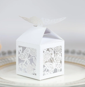 Detailed laser-cut ivory butterfly favor box on a porcelain plate for wedding events