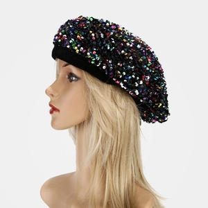 Detail view of a black velvet beret with colorful sequins on a mannequin model